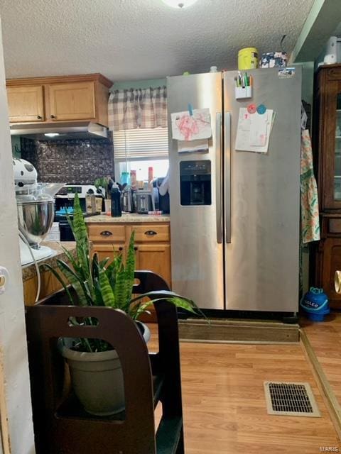 kitchen with light countertops, stainless steel refrigerator with ice dispenser, visible vents, and light wood-style floors