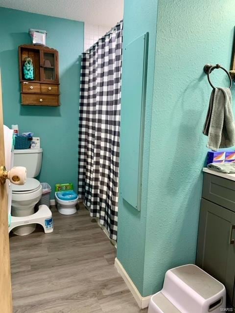 bathroom with toilet, baseboards, wood finished floors, and vanity