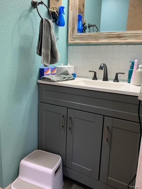 bathroom featuring a textured wall, backsplash, and vanity