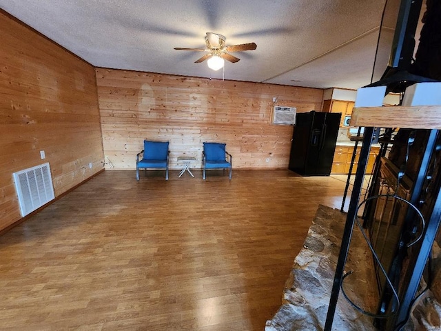 unfurnished room with a textured ceiling, wood finished floors, visible vents, and a ceiling fan