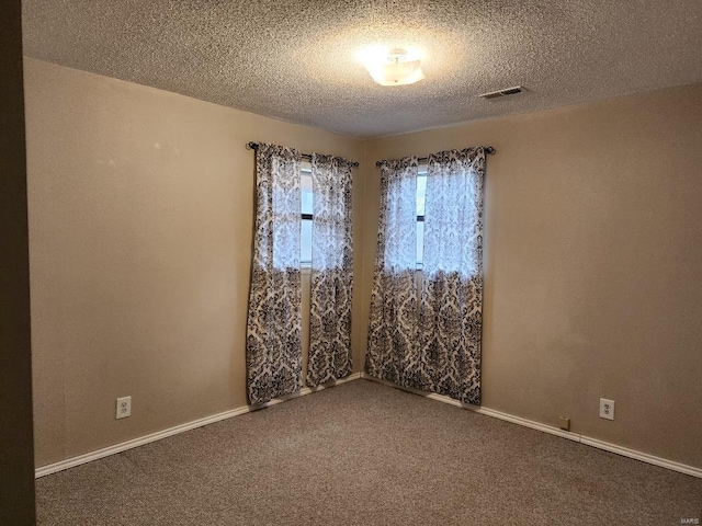 carpeted empty room with visible vents, a textured ceiling, and baseboards