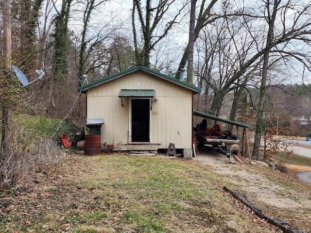 view of outbuilding featuring dirt driveway, an attached carport, and an outdoor structure