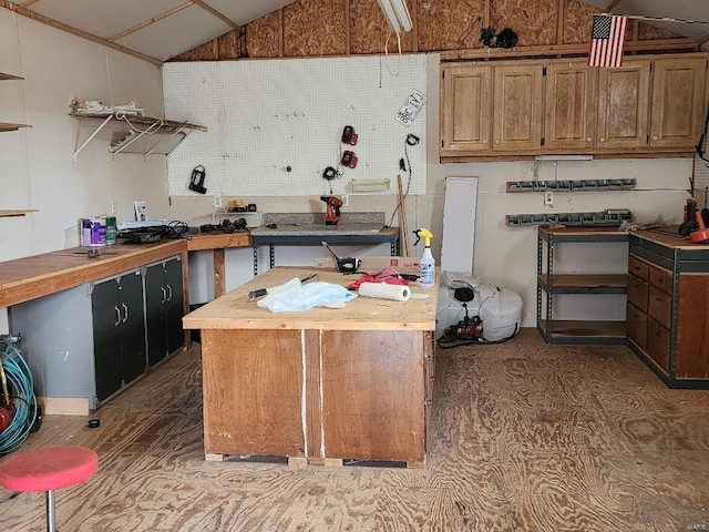 kitchen with vaulted ceiling, open shelves, butcher block countertops, and a center island