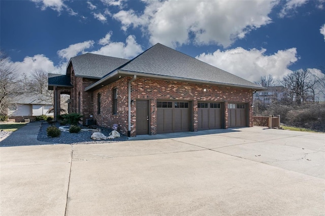 view of home's exterior with driveway, brick siding, roof with shingles, and an attached garage