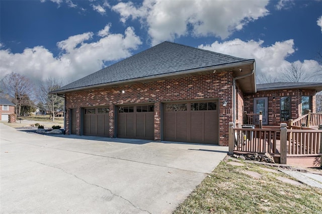 view of side of home with concrete driveway, brick siding, roof with shingles, and an attached garage