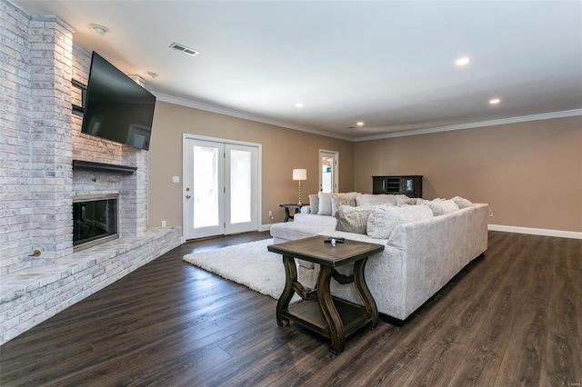 living area with baseboards, dark wood finished floors, crown molding, a brick fireplace, and recessed lighting