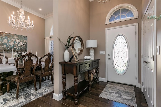 entryway with a notable chandelier, wood finished floors, a towering ceiling, baseboards, and ornamental molding