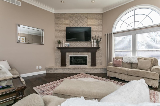 living room with visible vents, ornamental molding, a brick fireplace, wood finished floors, and baseboards