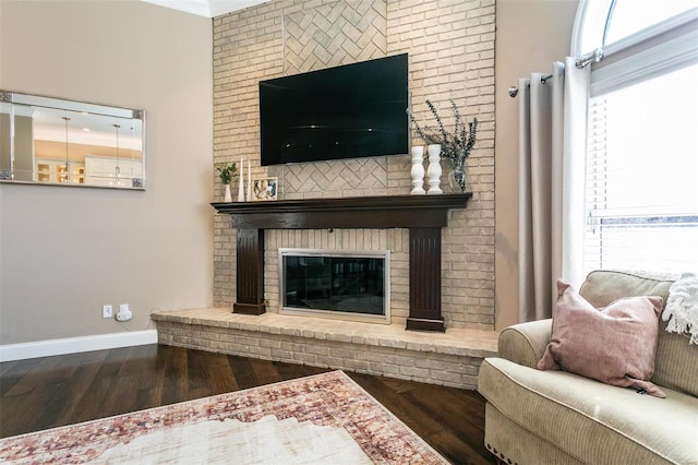 living room featuring a brick fireplace, baseboards, and wood finished floors