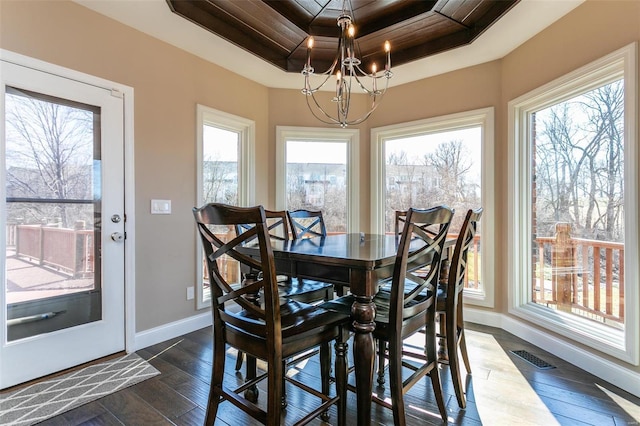 dining area featuring a healthy amount of sunlight, a raised ceiling, and dark wood-type flooring