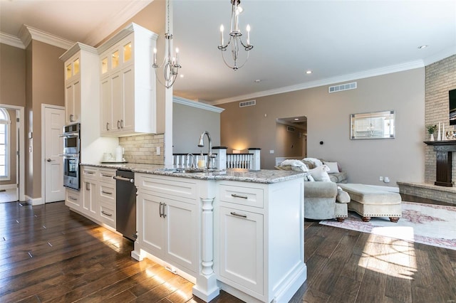 kitchen featuring stainless steel double oven, a peninsula, a sink, visible vents, and open floor plan