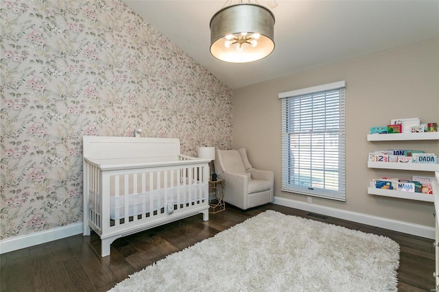 bedroom featuring a nursery area, baseboards, lofted ceiling, and wallpapered walls