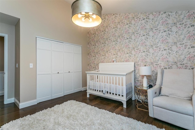 bedroom with baseboards, a closet, wood finished floors, and wallpapered walls