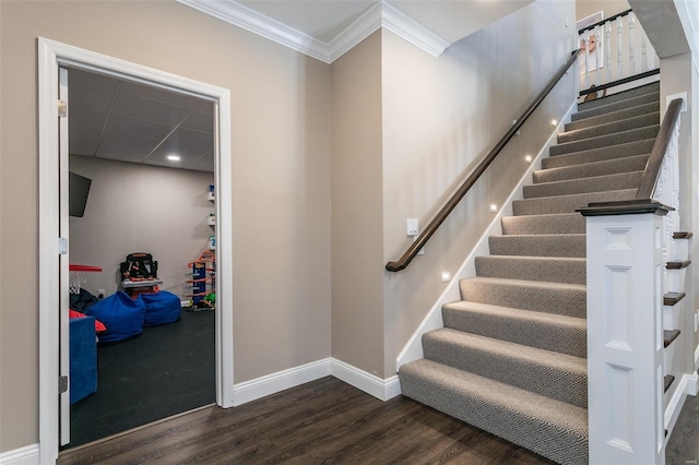 staircase with crown molding, baseboards, and wood finished floors