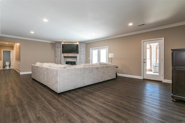 living area with ornamental molding, a large fireplace, dark wood finished floors, and baseboards