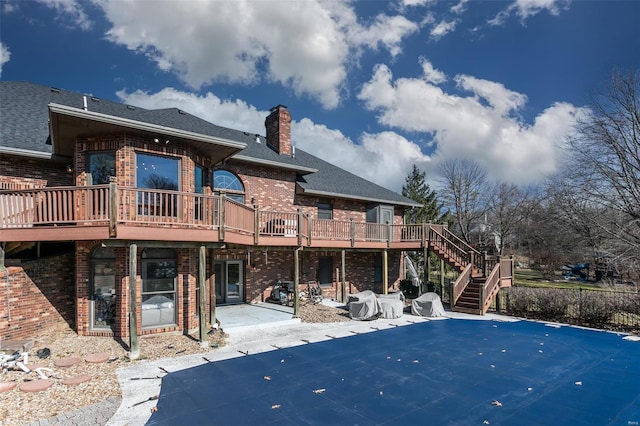 rear view of house with stairs, a chimney, a patio, and brick siding