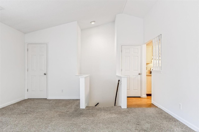 spare room featuring lofted ceiling, baseboards, and carpet floors