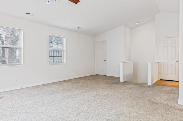 empty room with ceiling fan, visible vents, vaulted ceiling, and carpet flooring