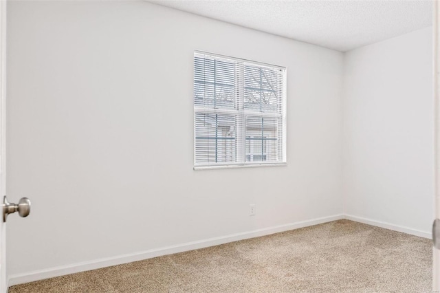 carpeted spare room with a textured ceiling and baseboards