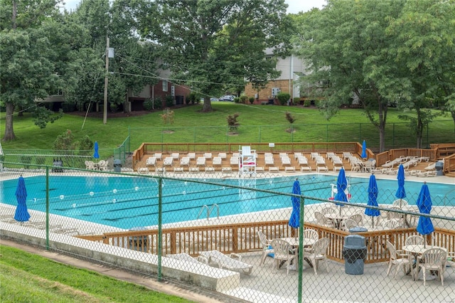 pool with a patio area, fence, outdoor dining area, and a lawn