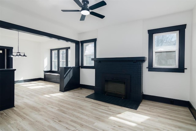 unfurnished living room featuring a fireplace, wood finished floors, and baseboards