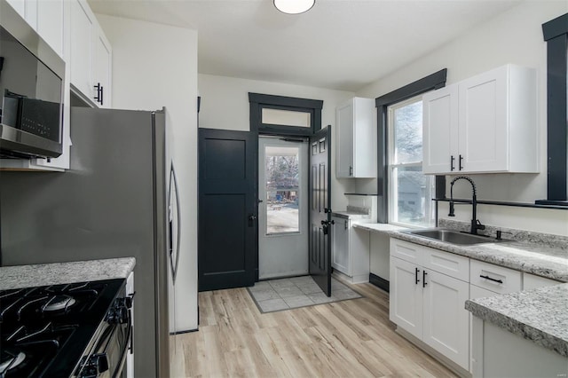 kitchen with white cabinetry, stainless steel microwave, and a sink