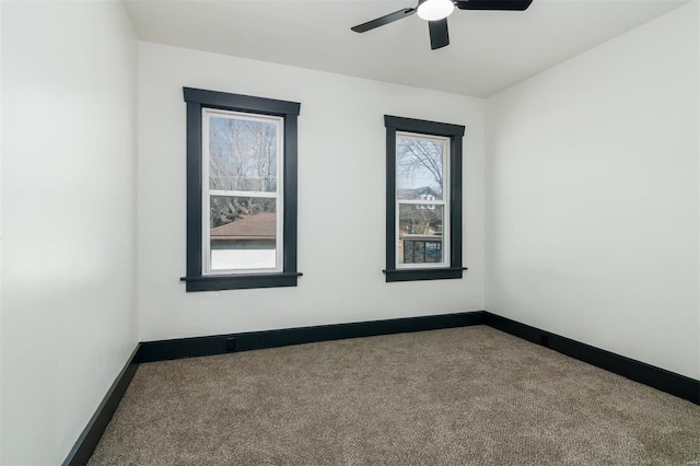 carpeted empty room with ceiling fan and baseboards