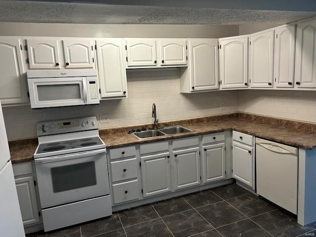 kitchen featuring dark countertops, white appliances, and a sink