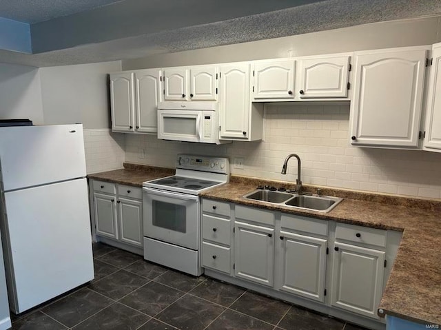 kitchen with dark countertops, white appliances, and a sink