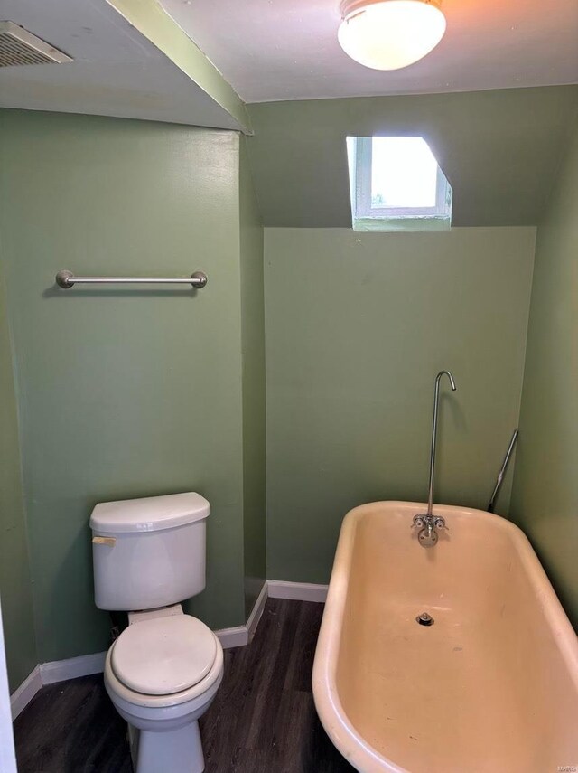 bathroom with a freestanding tub, visible vents, toilet, and wood finished floors