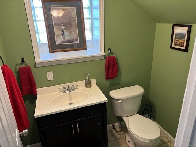 half bathroom featuring toilet, lofted ceiling, baseboards, and vanity