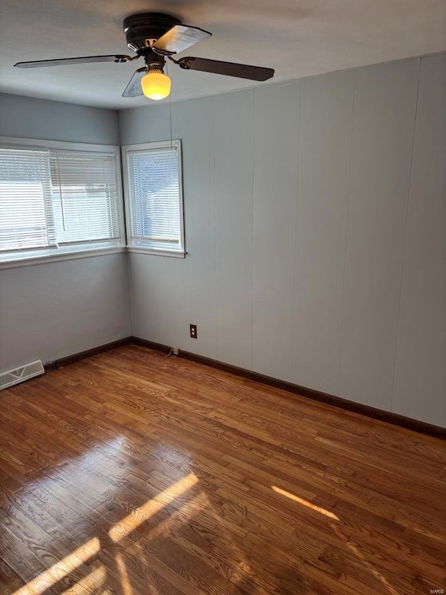 unfurnished room with a ceiling fan, visible vents, and wood finished floors