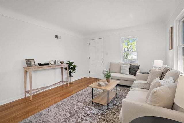 living room with visible vents, baseboards, and wood finished floors
