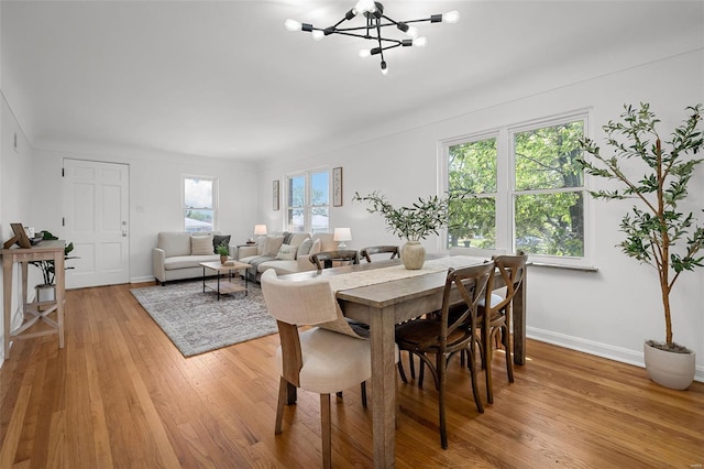 dining space with baseboards, an inviting chandelier, and light wood-style flooring