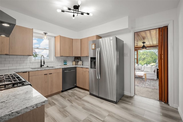 kitchen with light stone counters, a sink, appliances with stainless steel finishes, and light brown cabinets