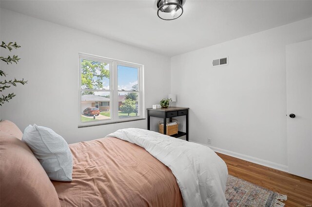 bedroom featuring baseboards, visible vents, and wood finished floors