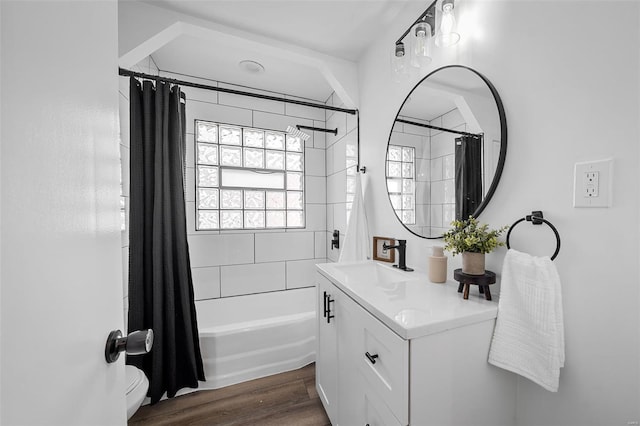 bathroom with toilet, wood finished floors, shower / tub combo, and vanity