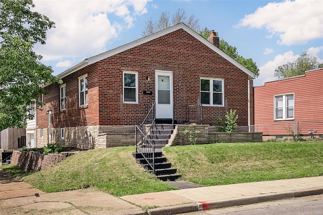 bungalow-style house with brick siding, a chimney, a front yard, and entry steps