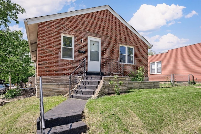 bungalow featuring brick siding, a front yard, and entry steps