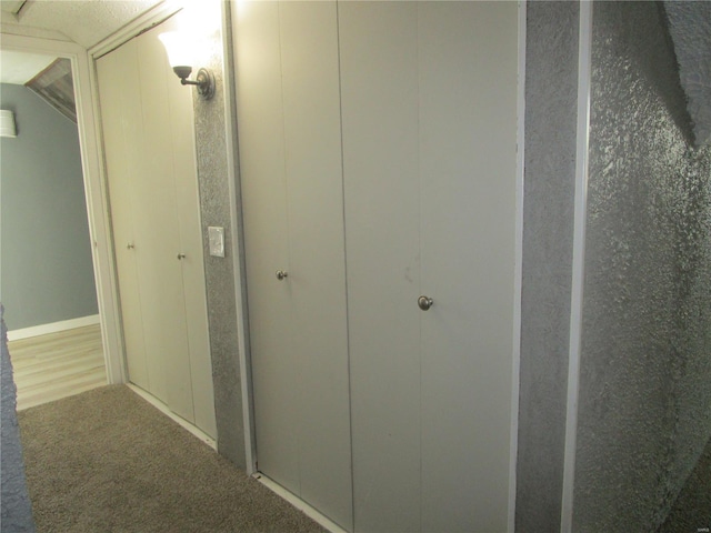 hallway featuring carpet flooring and lofted ceiling