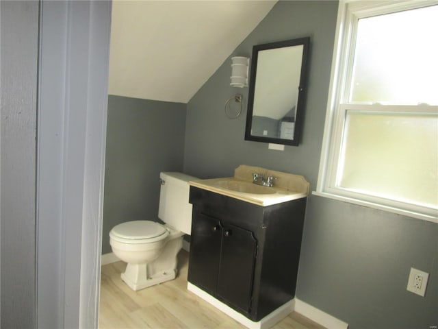 bathroom with toilet, lofted ceiling, wood finished floors, baseboards, and vanity