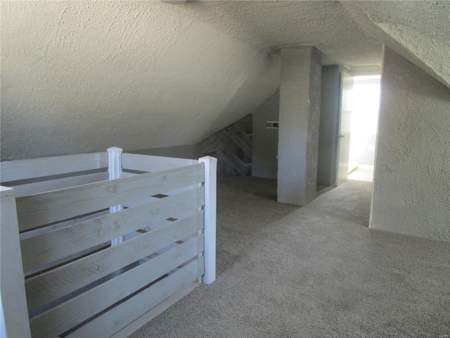 bonus room with carpet flooring, a textured ceiling, vaulted ceiling, and a textured wall