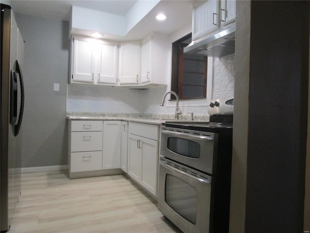 kitchen with under cabinet range hood, stainless steel appliances, light wood-type flooring, and white cabinetry