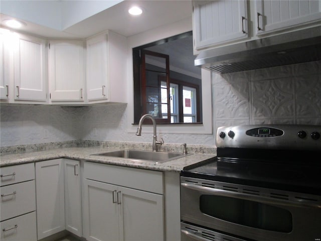 kitchen featuring stainless steel electric stove, a sink, white cabinets, under cabinet range hood, and backsplash