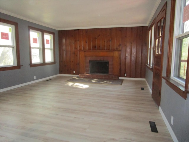 unfurnished living room with visible vents, a brick fireplace, light wood-type flooring, and ornamental molding