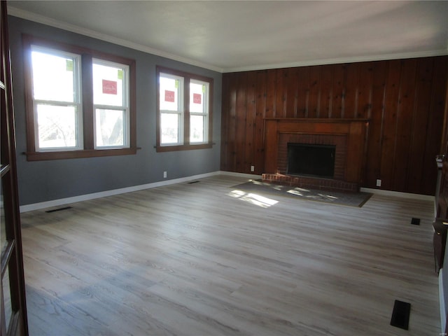 unfurnished living room featuring a brick fireplace, wood finished floors, baseboards, and ornamental molding