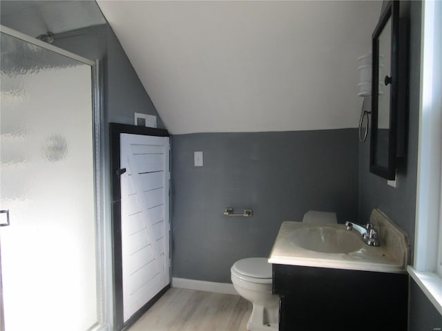 bathroom featuring baseboards, lofted ceiling, a stall shower, wood finished floors, and vanity