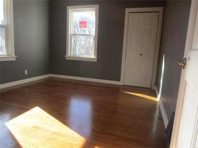 spare room featuring baseboards and wood finished floors