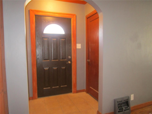 foyer entrance featuring baseboards, arched walkways, and light tile patterned flooring