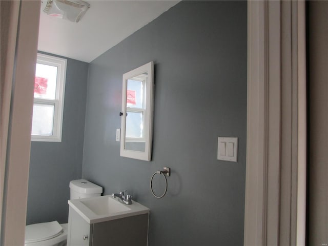 half bath with visible vents, toilet, and vanity